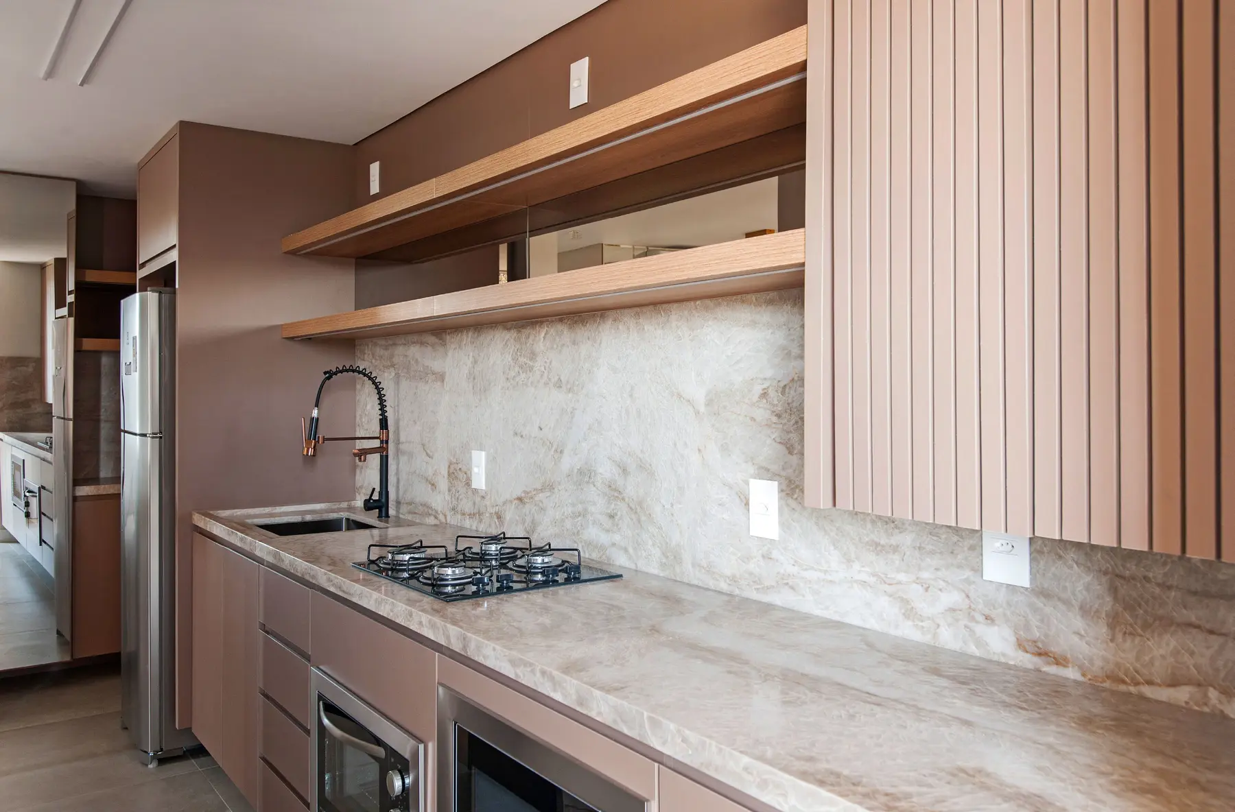Cozinha planejada com bancada e frontão em pedra clara